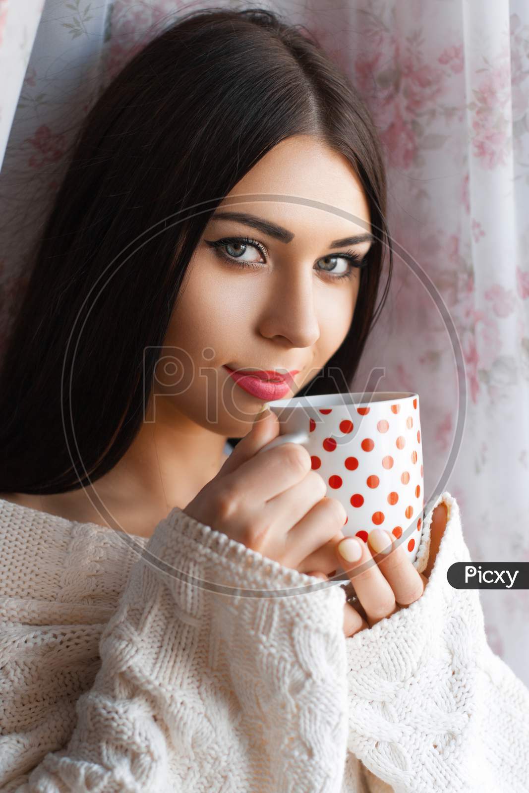 Beautiful Girl With Long Hair Drinking Coffee By The Window