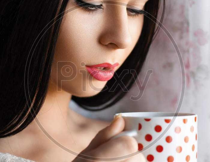 Beautiful Girl Drinking Coffee By The Window
