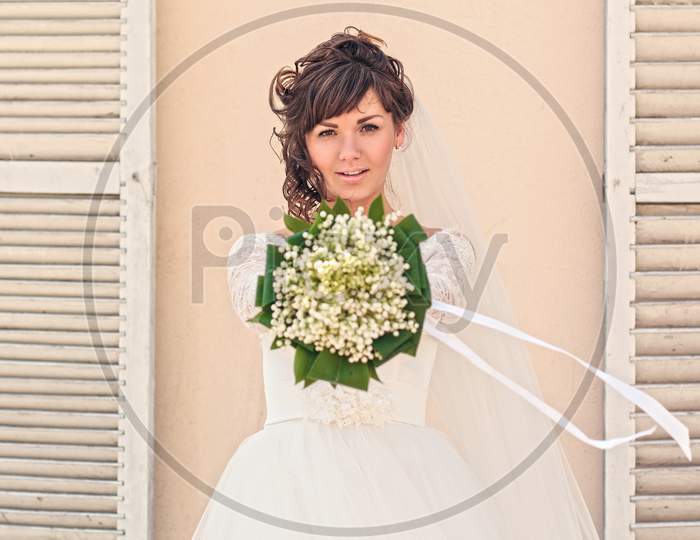 Girl With A Bouquet Of Flowers Standing At The Wall
