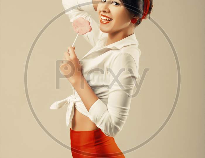 Pinup Woman With Candy Stands In Studio. Back To 1950S