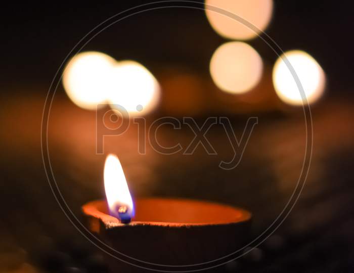 Portrait Photo Taken During Diwali Festival Night Of The Lit Clay Diya Oil Lamp With Orange Light Bokeh As Background.