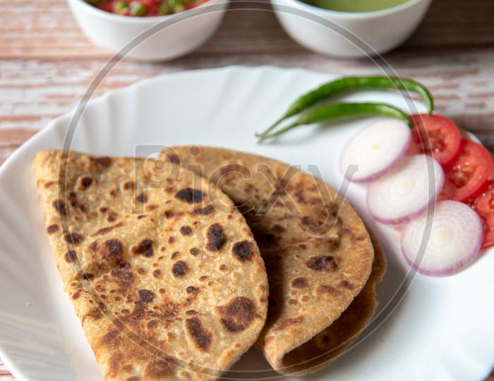 Alu Paratha along with vegetable salad in a plate along with condiments