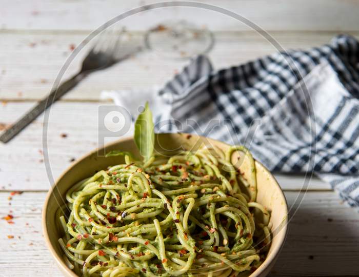Close up of spaghetti with pesto sauce in a bowl