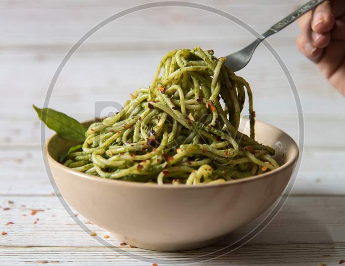 Spaghetti pasta in pesto sauce lifted from a bowl