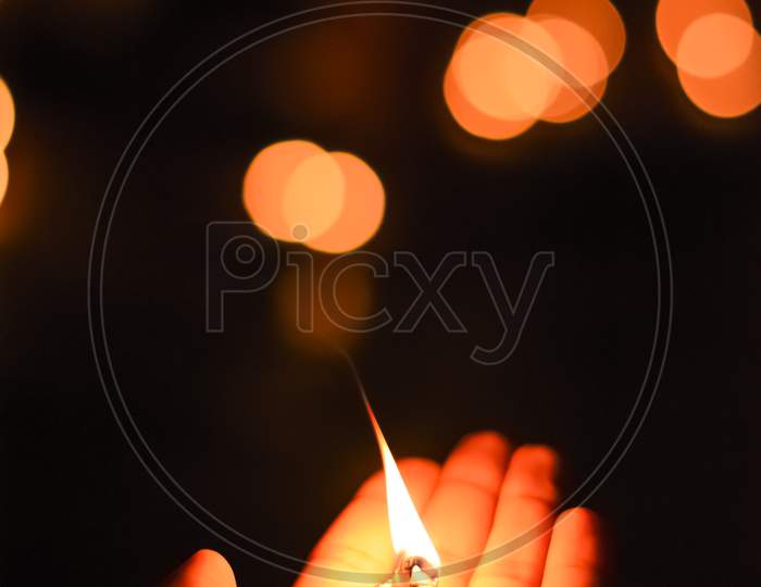 Portrait Photo Taken During Diwali Festival Night Of The Lit Clay Diya Oil Lamp Held In The Hand With Orange Light Bokeh As Background.