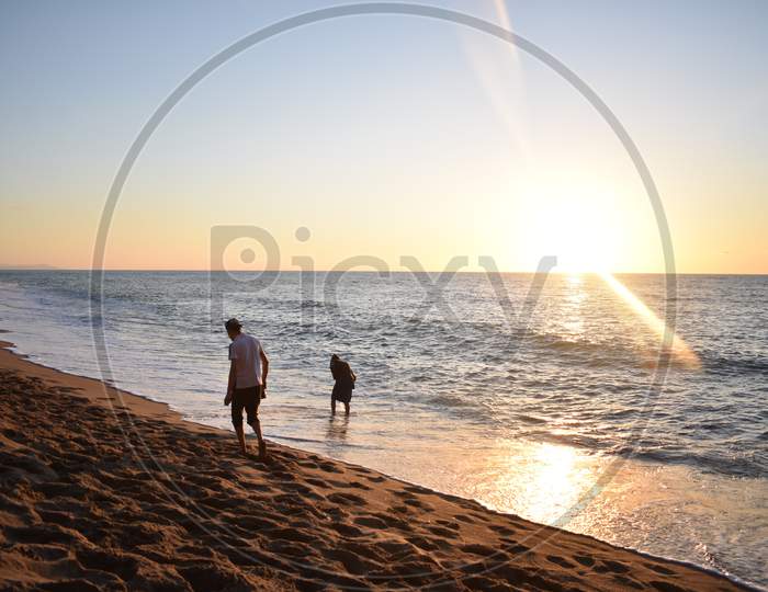 two people walking in beach while sunset summer 2019