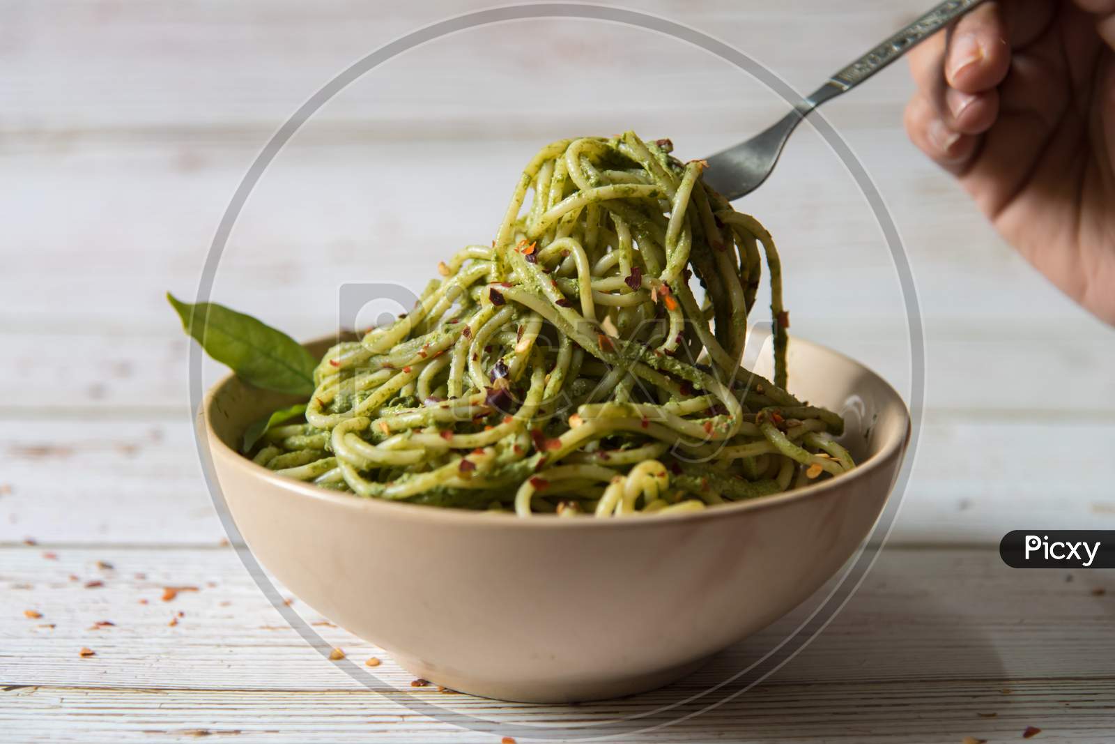 Spaghetti pasta in pesto sauce lifted from a bowl