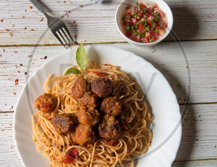 Top view of spaghetti pasta and meatballs in a plate along with condiments