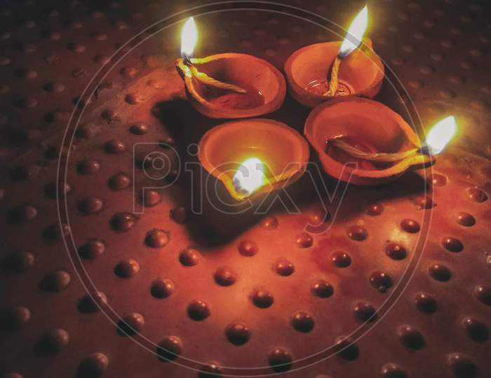 Photo Of A Four Lit Clay Diya Oil Lamps Placed In The Floor, Taken During Diwali Festival Night.
