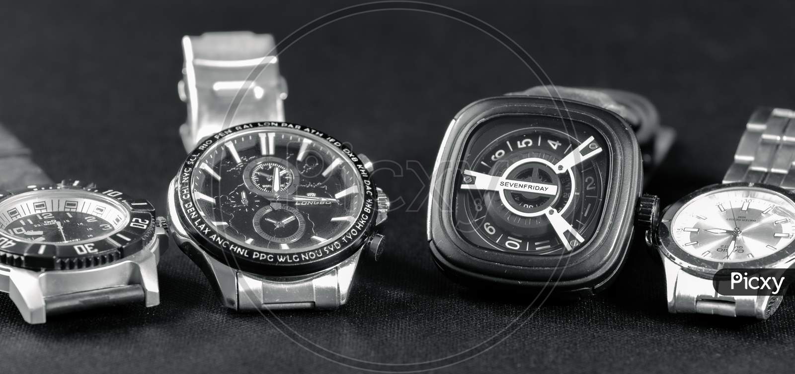 Four Watches Lined In A Dark Grey Surface.