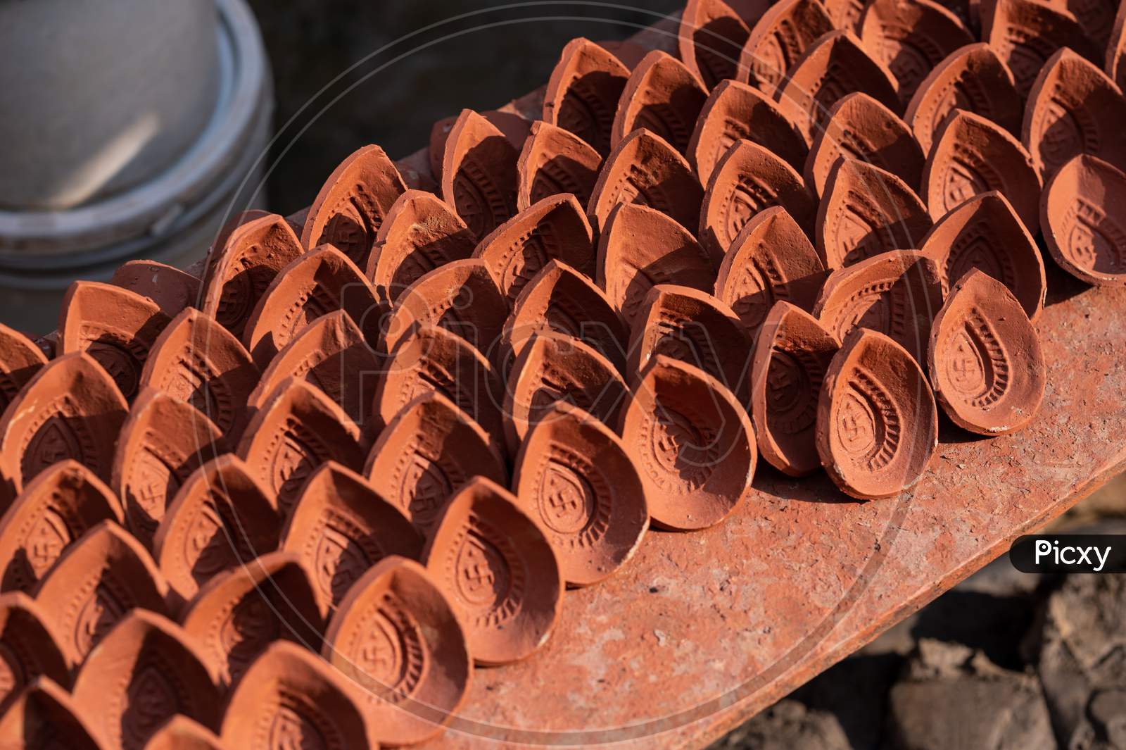 Traditional diya made of clay and mud placed in sunlight at Diya factory in Rural India.