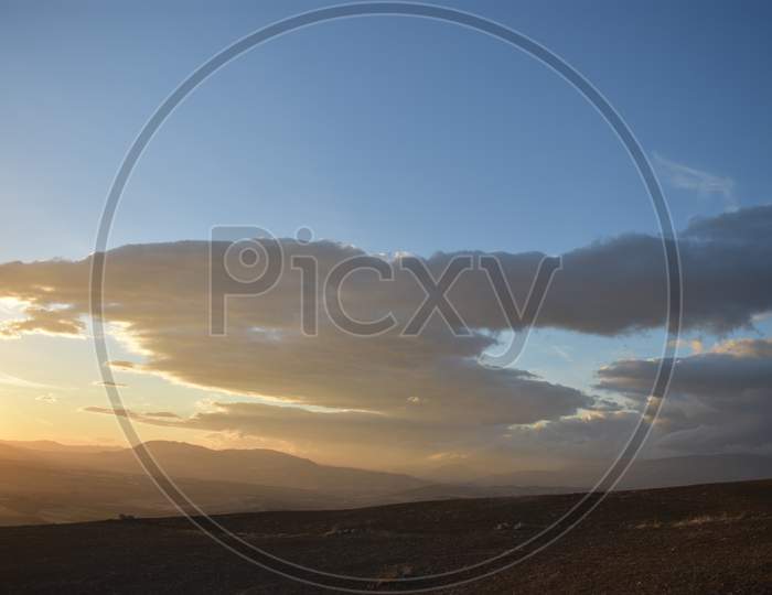 cloudy day  landscape mountains touching cloudswith sunset in the back