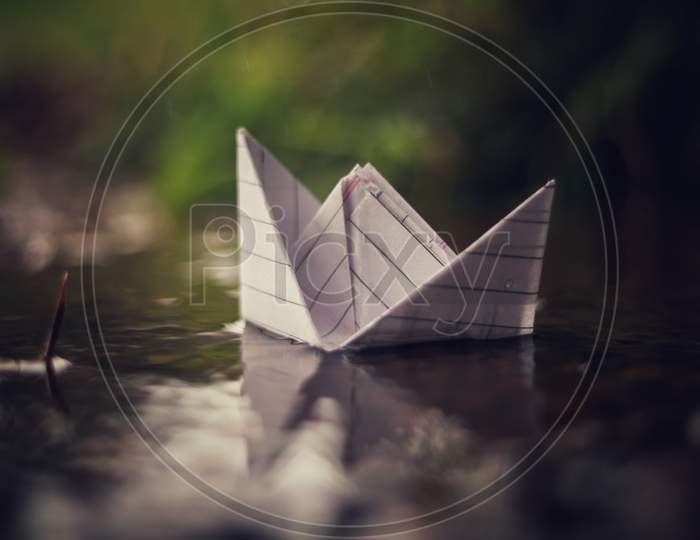 A paper boat floating on rainy water in rainy season