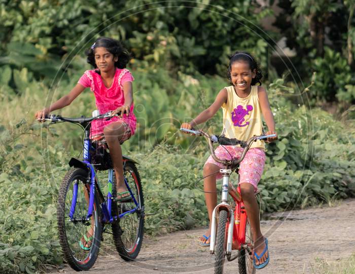 Southern Province / Sri Lanka - 10 24 2020: Two Children Ride Bikes In The Rural Streets Enjoying And Smiling.