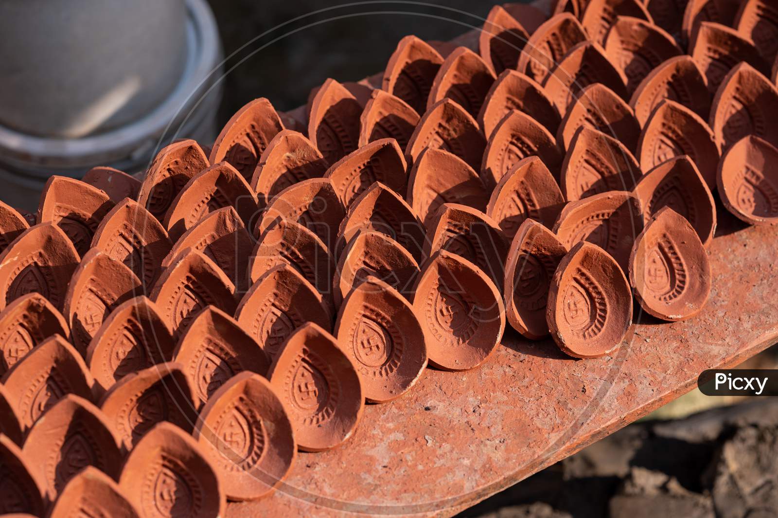 Traditional diya made of clay and mud placed in sunlight at Diya factory in Rural India.
