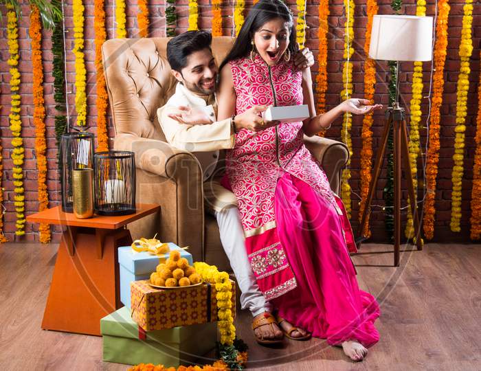 Indian Young Couple Celebrating Birthday, Anniversary Or Diwali Festival With Boondi Laddoo & Gifts