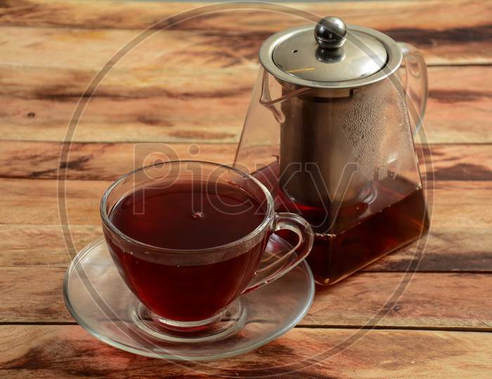 Freshly Brewed Cranberry Apple Tea In Glass Cup With Tea Pot On Rustic Wooden Background, Selective Focus