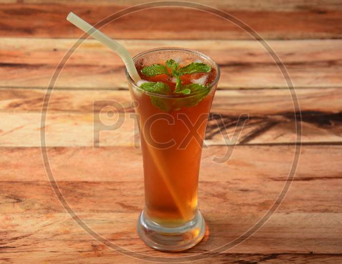 Traditional Iced Tea In A Glass With Mint And Paper Straws On A Rustic Wooden Background.