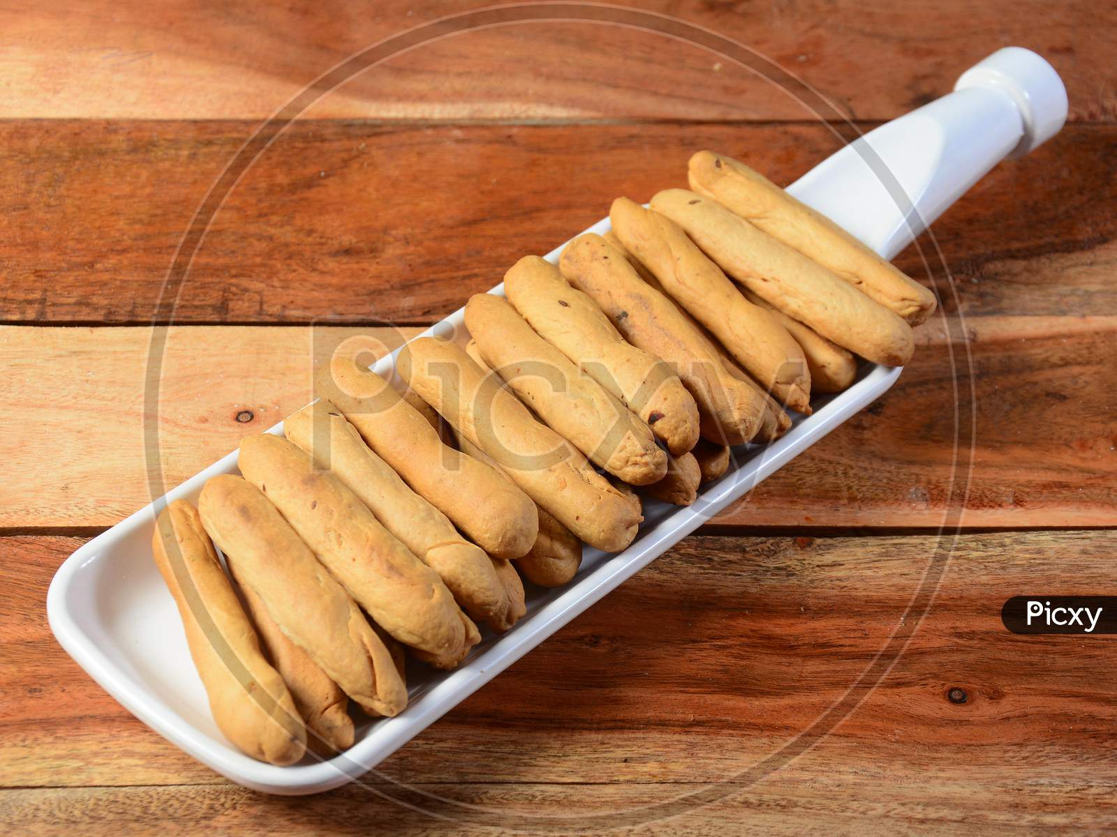 Freshly baked golden bread sticks on white plate, selective focus