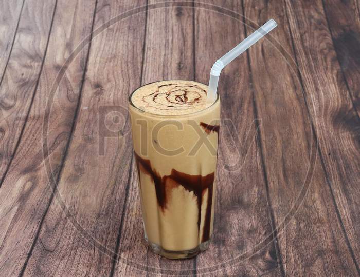 Thick Cream Cold Coffee In A Tall Glass With Cream Poured On A Old Rustic Wooden Table.