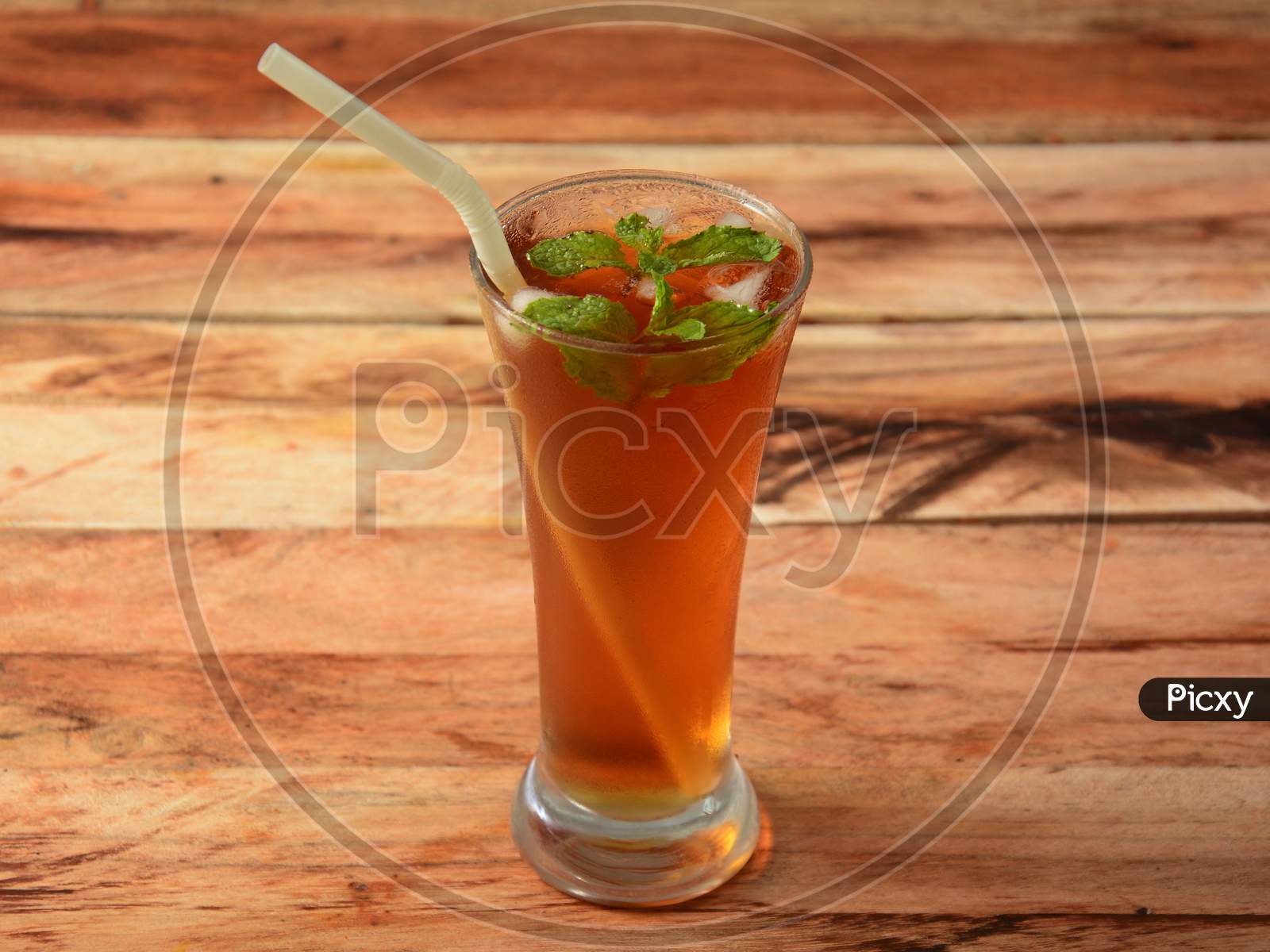 Traditional Iced Tea In A Glass With Mint And Paper Straws On A Rustic Wooden Background.