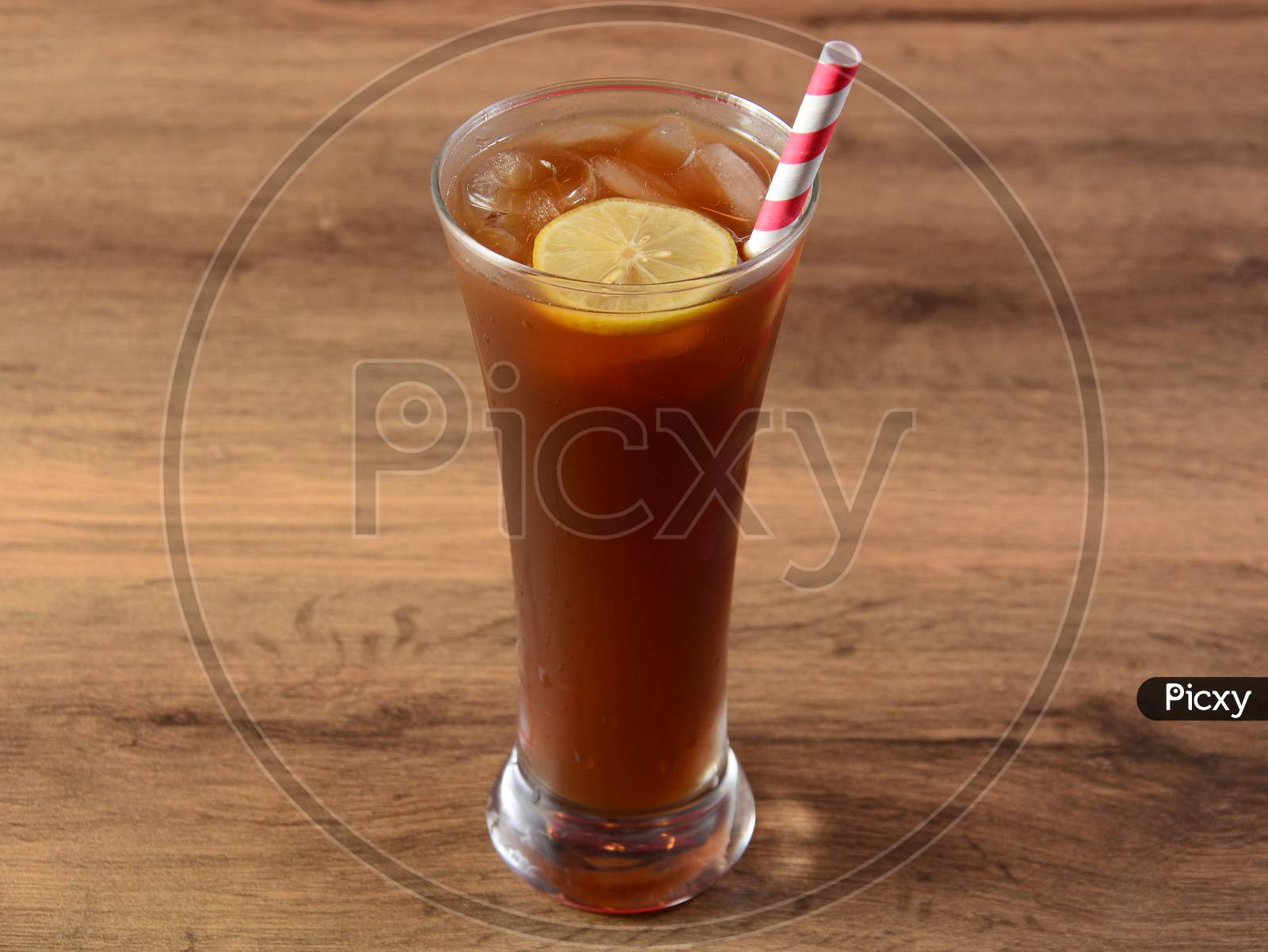 Traditional Iced Tea In A Glass With Lemon And Paper Straws On A Rustic Wooden Background.