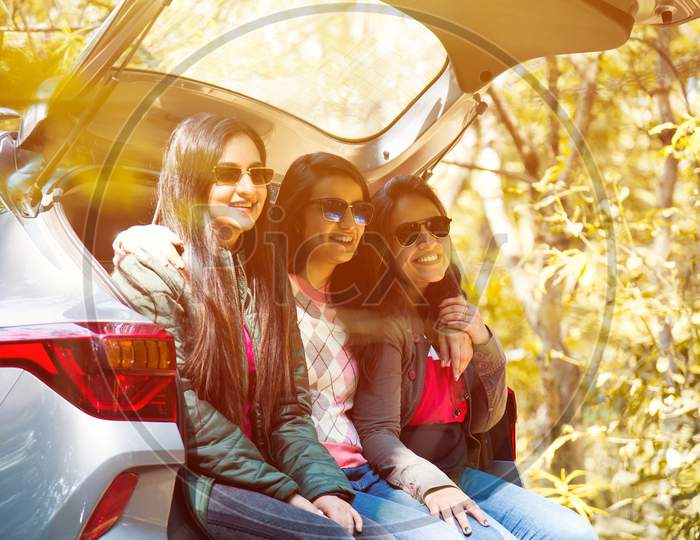 Group Of Asian Indian Friends On Trip Sitting In Trunk Of Car