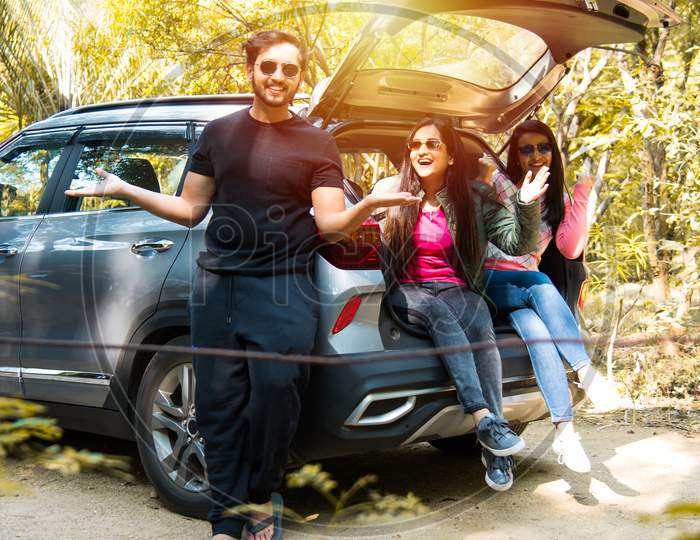 Group Of Asian Indian Friends On Trip Sitting In Trunk Of Car