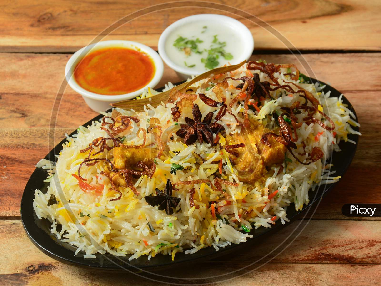 Traditional Hyderabadi Chicken Dum Biryani Made Of Basmati Rice Cooked With Masala Spices, Served With Onion Raita And Salan, Selective Focus