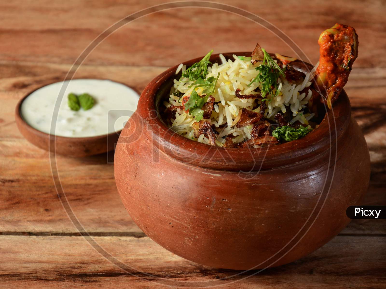 Traditional Murgh Dum Biryani Made Of Basmati Rice Cooked With Masala Spices, Served With Yogurt On Traditional Clay Pot, Selective Focus