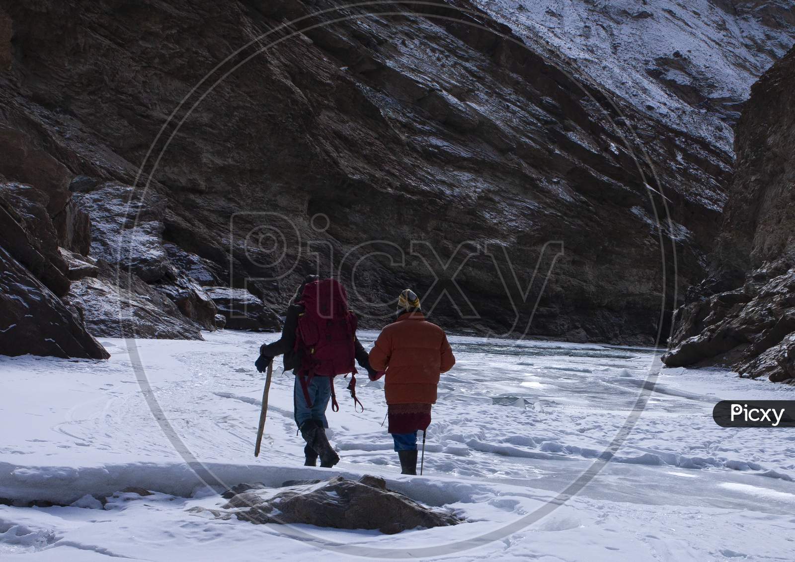 Adventurous High Altitude Trekking On The Frozen Zanskar River [ Known As Chadar Trek ] In Winter In Ladakh In India Carrying Rucksack And Walking Stick