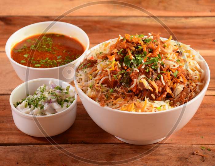 Traditional Hyderabadi Chicken Dum Biryani Made Of Basmati Rice Cooked With Masala Spices, Served With Onion Raita And Salan, Selective Focus