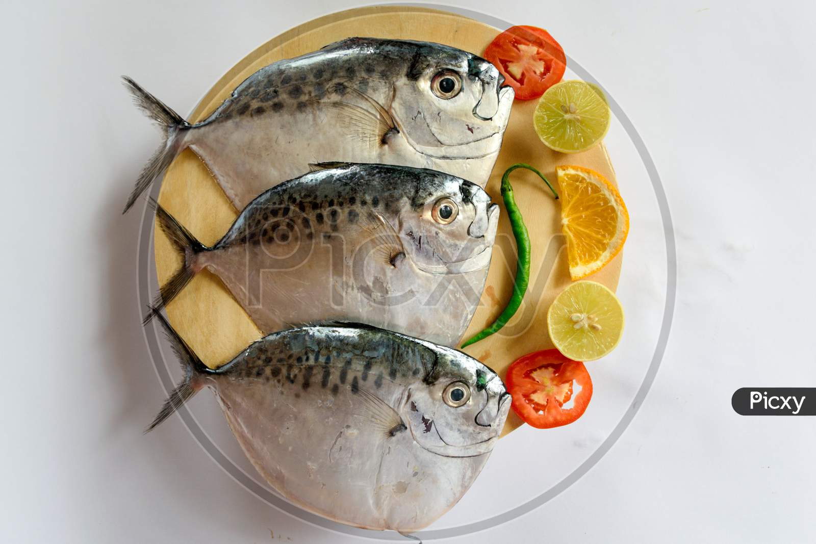 Fresh Razor Moonfish/Razor Trevally Fish, Decorated With Herbs And Lemon Slice On A Wooden Pad.
