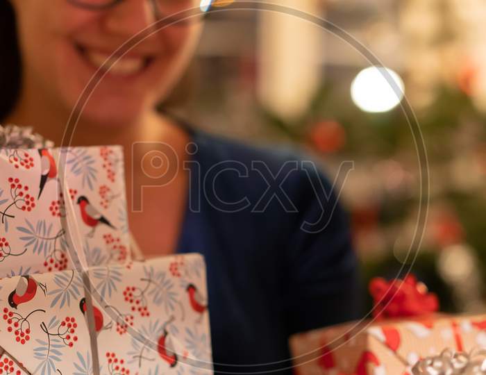 Smiling Girl Presenting Gifts In Lovely Boxes With Bird Design At Christmas Eve.