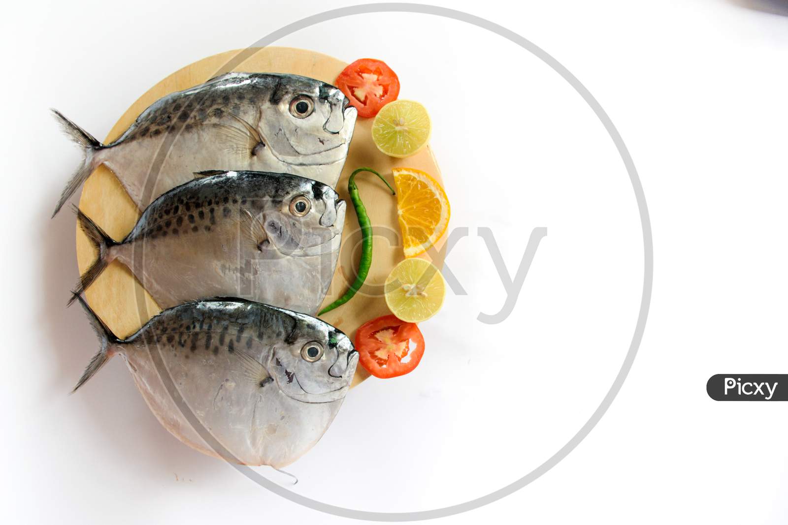 Fresh Razor Moonfish/Razor Trevally Fish, Decorated With Herbs And Lemon Slice On A Wooden Pad