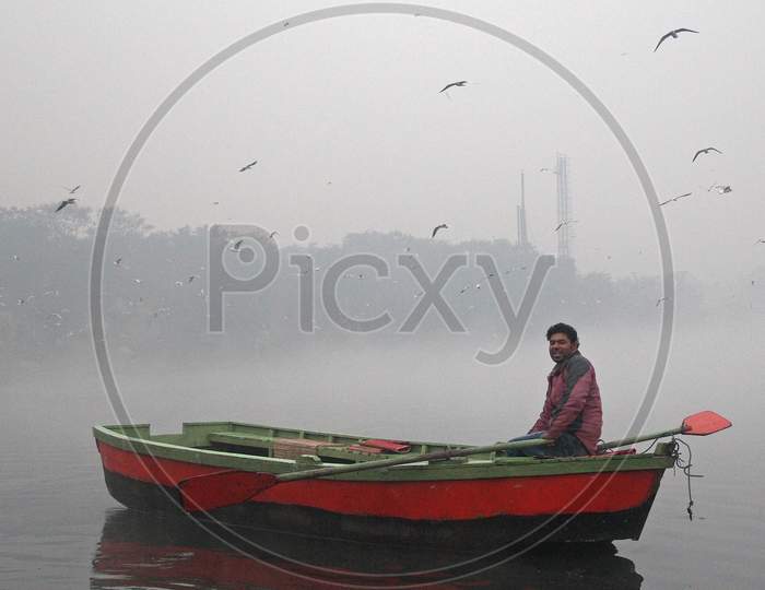 A man rides a boat in the Yamuna river on a smoggy morning in New Delhi, November 9, 2020.