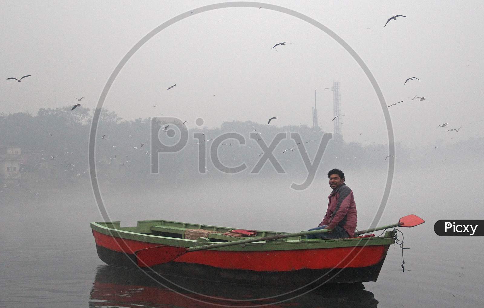 A man rides a boat in the Yamuna river on a smoggy morning in New Delhi, November 9, 2020.