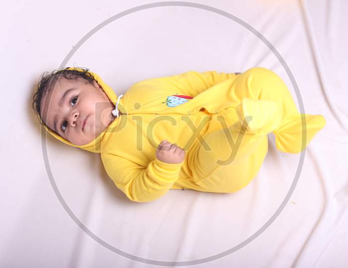 Cute baby wearing yellow clothes and playing on the ground