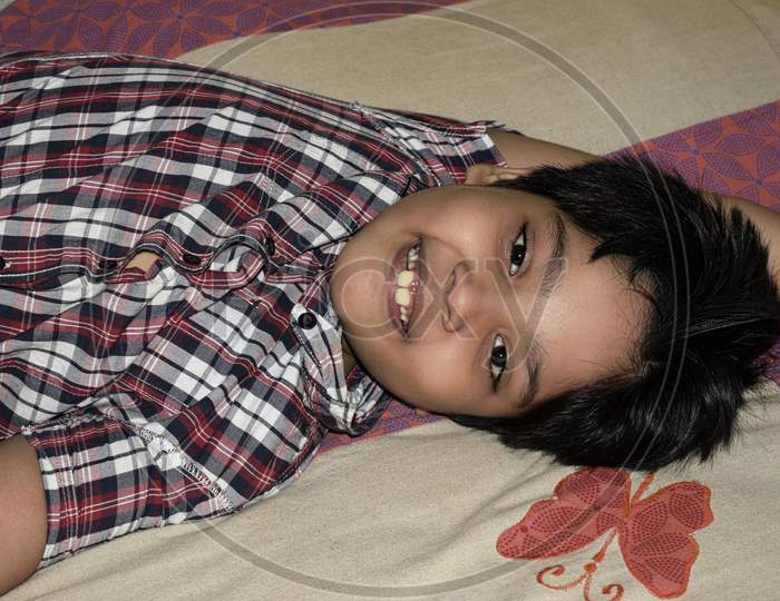 indian boy laying on bed with a happy smile