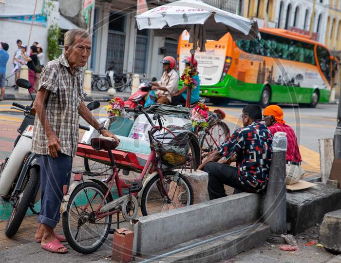 An Old Man Stand Beside The Bicycle At Street