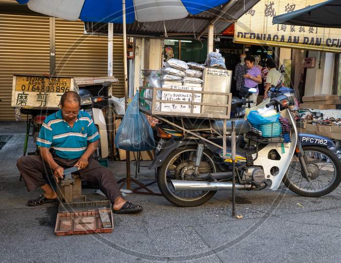 A Man Provide Service Sharpening The Scissors At Market