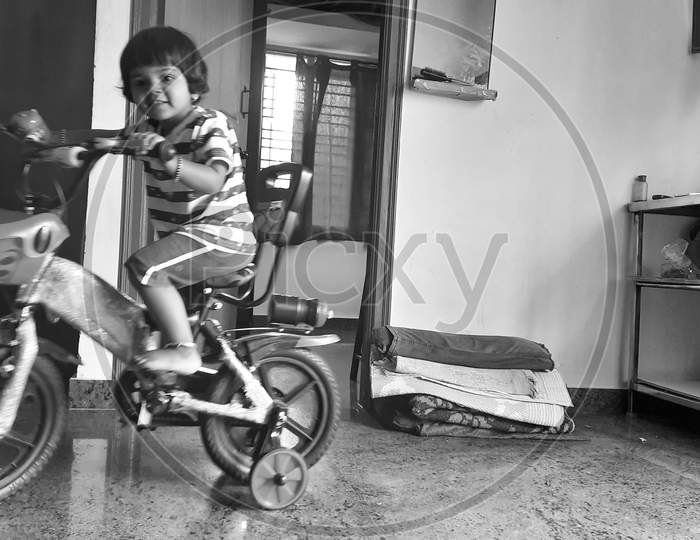 Indian girl kid learning or riding small bicycle inside the home
