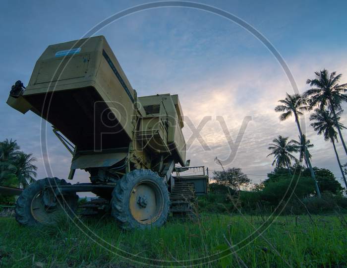 Low Angle Harvester Park In Field During Sunset