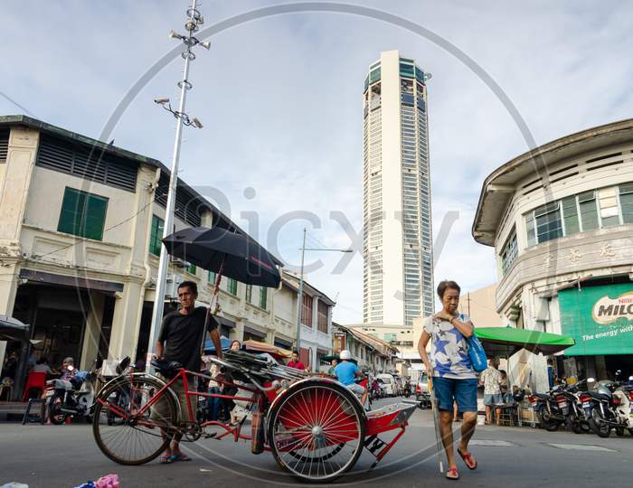A Trishaw Driver Rest In Front Of Show Stall. Background Is Komtar Building