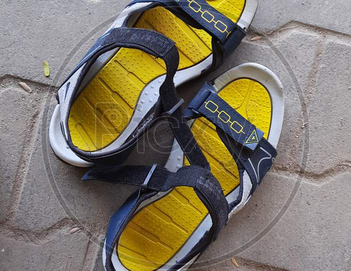 Closeup of Pair Yellow and blue Color New Sandals in a Empty Road