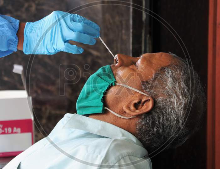 A health worker in personal protective equipment (PPE) collects a swab sample from a man during a rapid antigen testing campaign for the coronavirus disease (COVID-19), on a street in Mumbai, India, November, 2020.