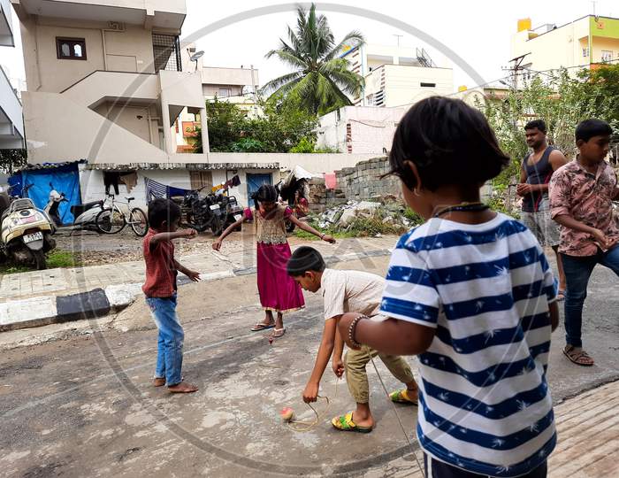 Image of Closeup of different age group kids playing Buguri or Spinning ...