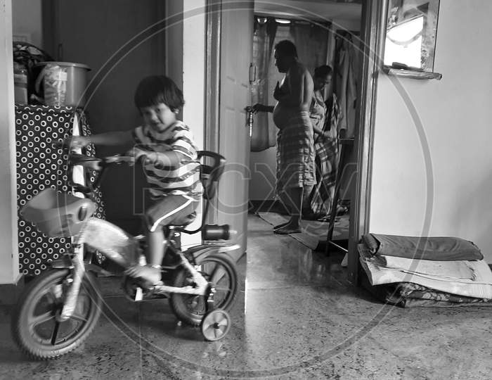 Indian girl kid learning or riding small bicycle inside the home