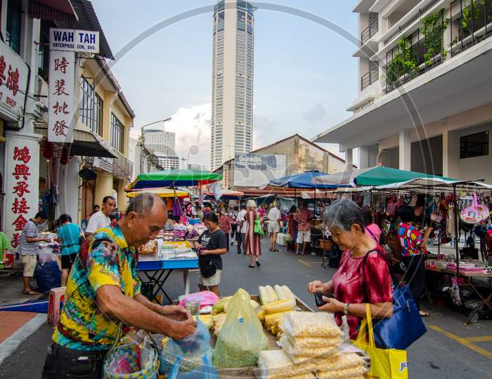 Woman But Food At The Morning Market. Back Is Komtar Building