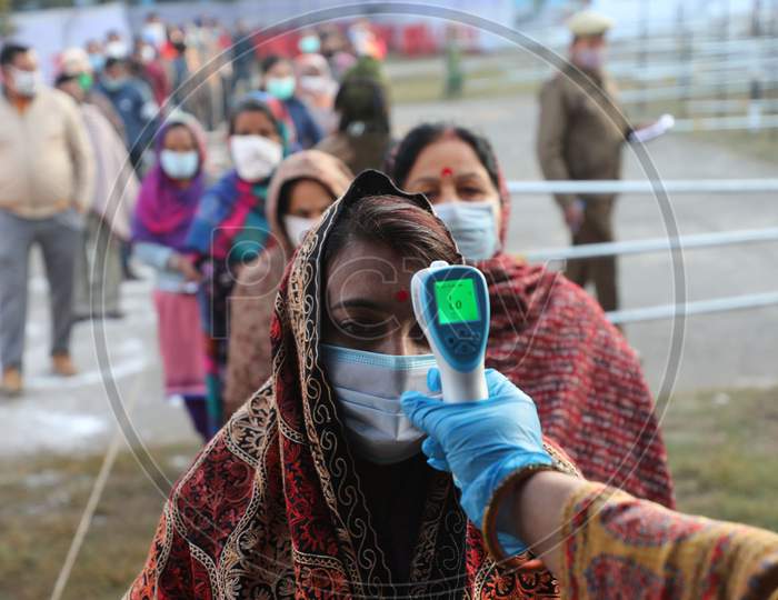 People arriving at a polling station undergo thermal screening during the Fifth phase of the District Development Council (DDC) elections at Phalya Mandal Village outskirts in Jammu .10 Dec.2020.